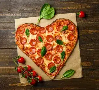 Pizza in Herzform mit Tomaten und Basilikum