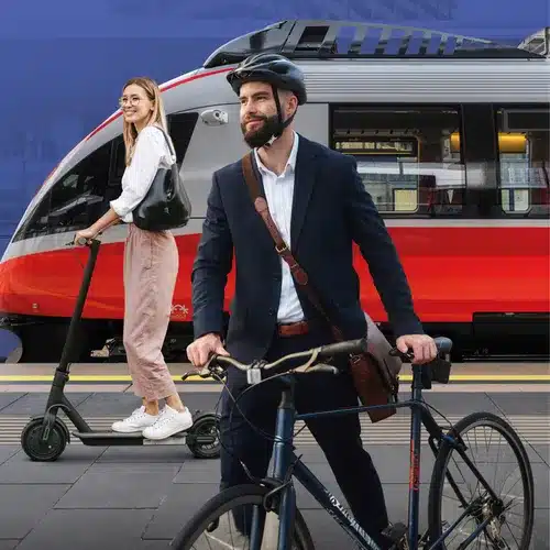 Darstellung verschiedener Mobilitätsarten auf einen Blick (Zug im Hintergrund, Frau die einen E-Roller fährt und ein Mann mit einem Fahrrad).