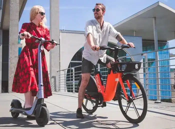 Frau mit E-Roller und Mann mit E-Bike.