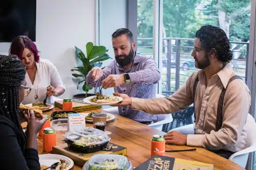 Essenszuschuss: Kollegen sitzen zusammen am Tisch und essen