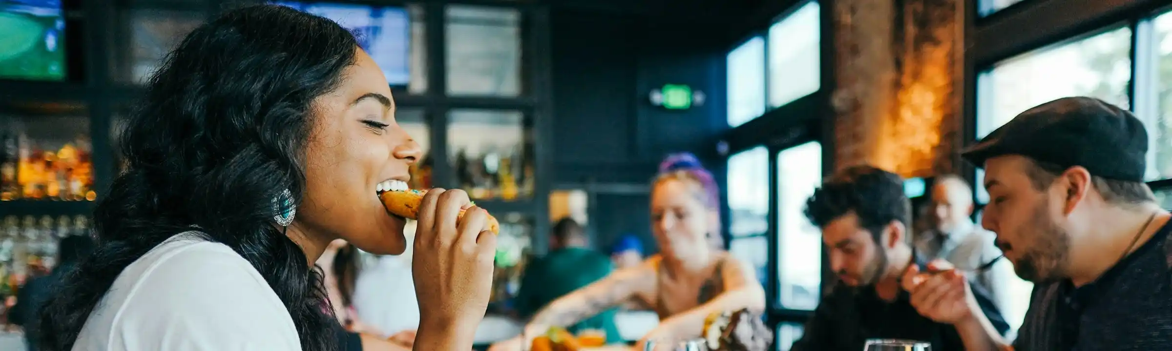 Mitarbeiterverpflegung in KMU: ein paar Kollegen sitzen zusammen an einem Tisch und essen gemeinsam zu mittag.