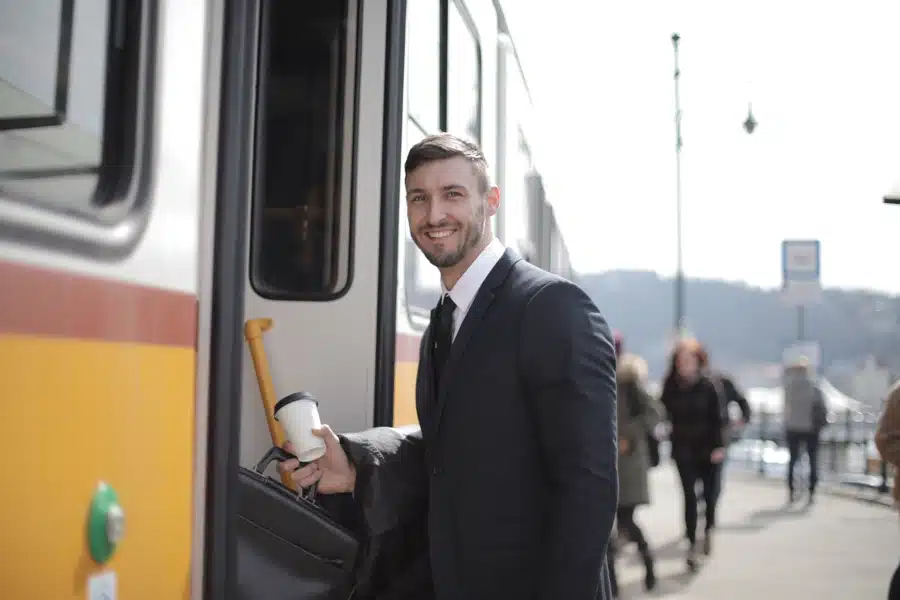 Fahrgast mit Smartphone am Bahnsteig vor einem Regionalzug